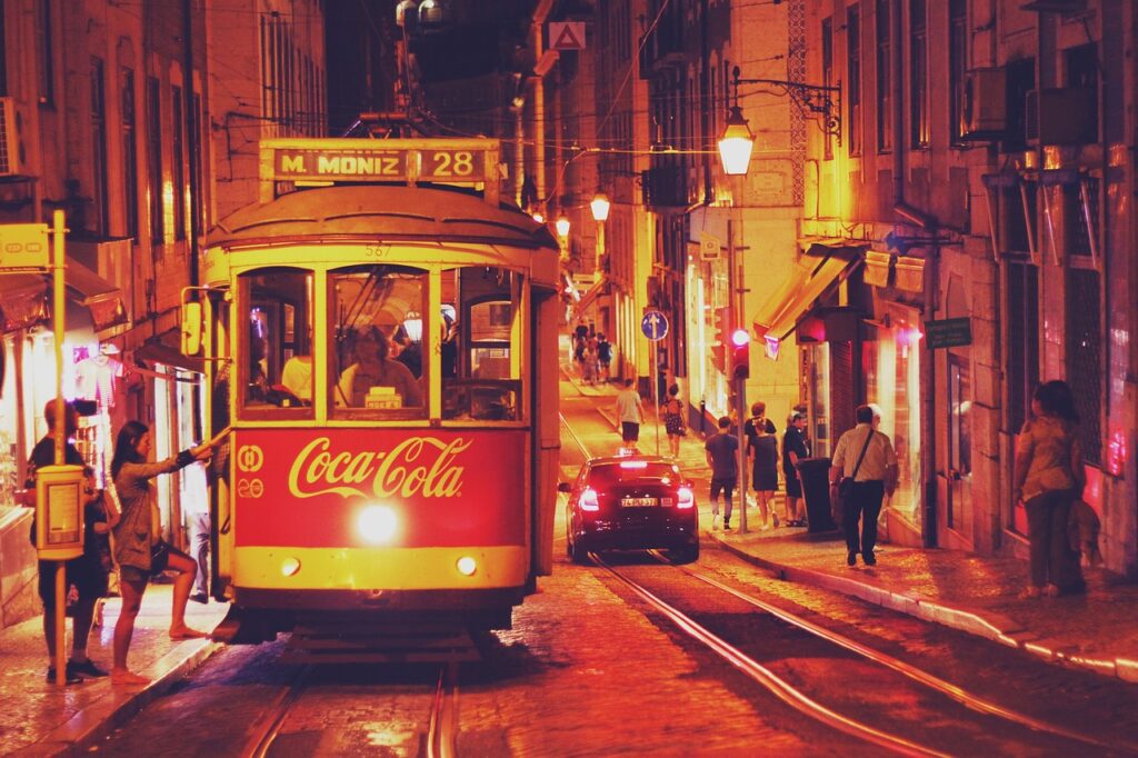 the 28 Tram in Lisbon at nighttime being boarded by passengers.